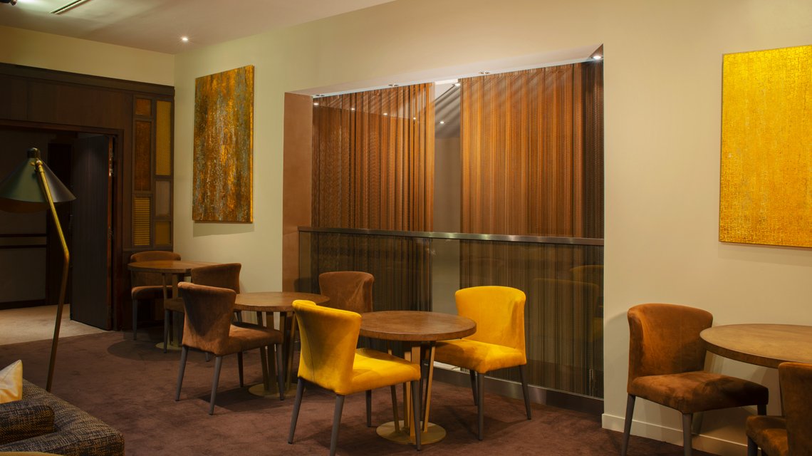 Revestimento mural e divisória em malha metálica decorativa – Hotel Paris - <p>Revestimento mural e separação decorativa em malha metálica MIES com acabamento efeito enferrujado num espaço hoteleiro em Paris. Solução arquitetónica sob medida para estruturar volumes mantendo transparência e leveza visual.</p>